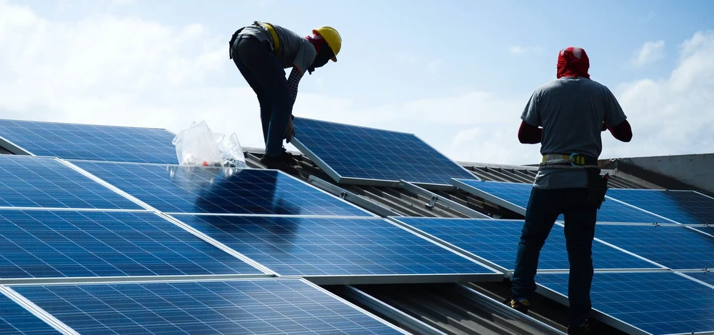 Deux techniciens installent des panneaux photovoltaïques sur une toiture industrielle