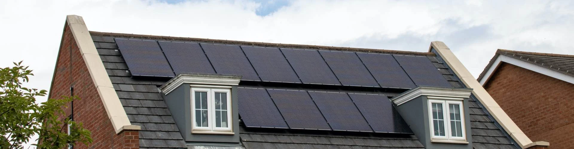 Maison individuelle de style alsacien, enduit clair, toiture en ardoise équipée de panneaux photovoltaïques monocristallins noirs